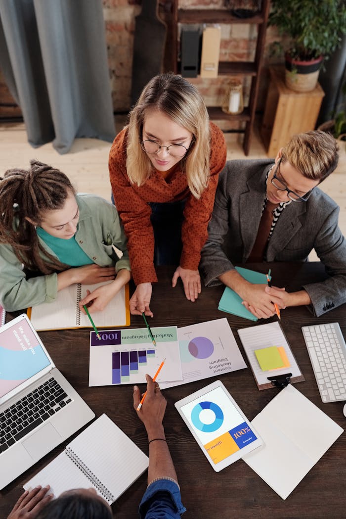 why-choose-us Top view of a diverse group discussing business reports and charts around a desk.