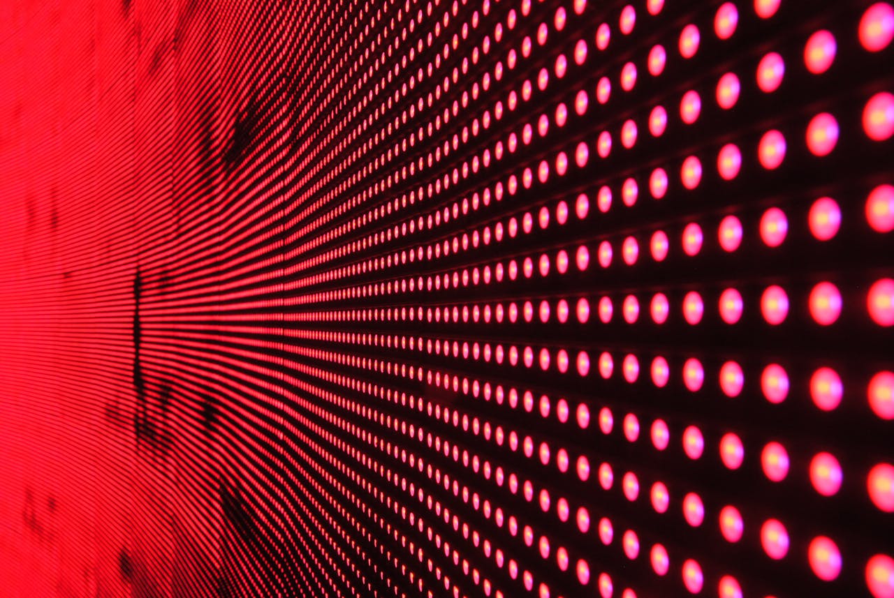 hero-img-01 Vibrant abstract pattern of illuminated red LED lights forming a dynamic design.